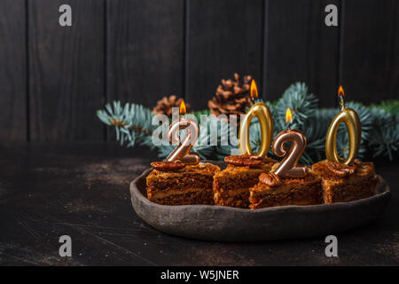 Das neue Jahr 2020. Festliche Kuchen mit Kerzen auf einem dunklen Hintergrund, kopieren. Stockfoto