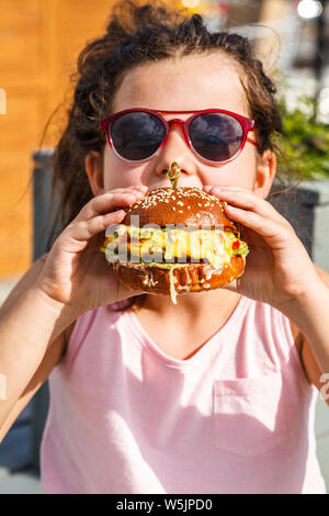 Kleines Mädchen einen Burger essen auf der Straße. Stockfoto