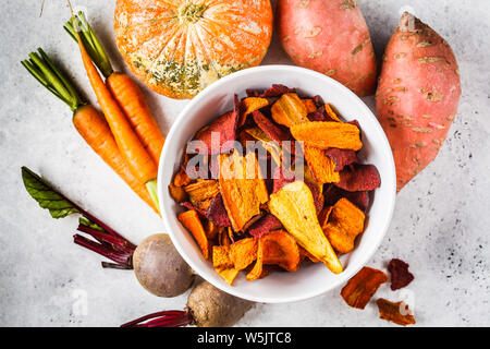 Schüssel gesunde Gemüse Chips aus Rüben, süsse Kartoffeln und Karotten mit Zutaten auf einem weißen Hintergrund. Stockfoto