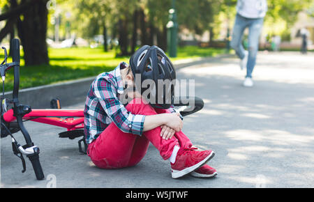 Schreiende Mädchen in der Helm sitzt auf dem Park Road Stockfoto