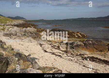 East Kilbride South Uist und schaut in den Causeway nach Eriskay, mit Strand und Felsen im Vordergrund. Stockfoto