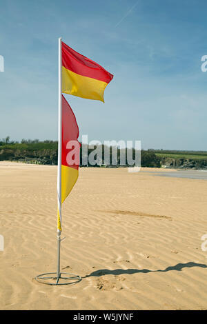 Rote und gelbe Flaggen an einem sonnigen Tag an einem sandigen Strand fliegen Cornwall Stockfoto