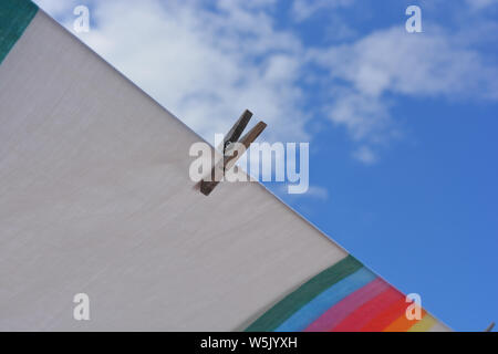 Rainbow farbige Blatt auf dem Trockenen sitzen, weht im Wind, auf der Wäscheleine an sonnigen, windigen Tag. Selektiver Fokus auf einzelne Holz Wäscheklammer Stockfoto