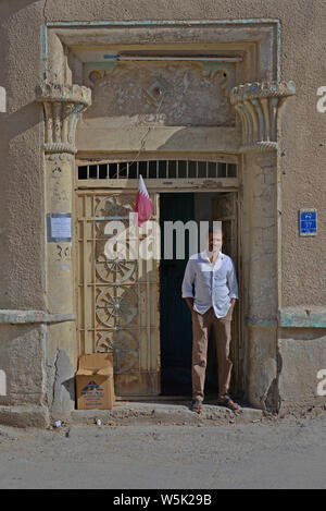 DOHA, Katar - MÄRZ 25, 2016: Ein indischer expat Mann steht im Türrahmen eines alten Gebäudes in der Straße von einem beliebten Stadtteil von Doha. Erstellt am Stockfoto