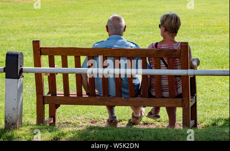 Ein älteres Ehepaar genießen Sie eine ruhige Zeit auf einer Parkbank in Broadway, Worcestershire, England, Großbritannien Stockfoto