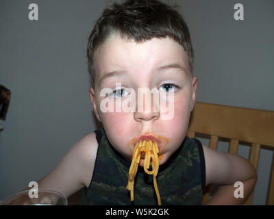 Junge herum und Grimassen, während er isst Spaghetti Bolognese Stockfoto