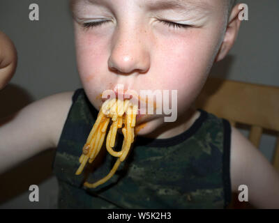 Junge herum und Grimassen, während er isst Spaghetti Bolognese Stockfoto