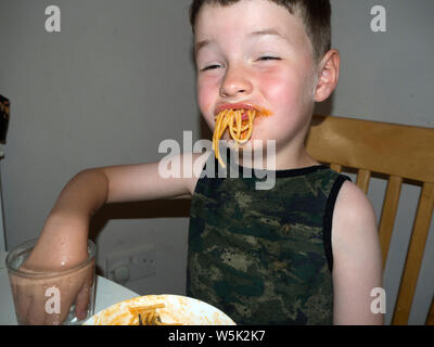 Junge herum und Grimassen, während er isst Spaghetti Bolognese Stockfoto