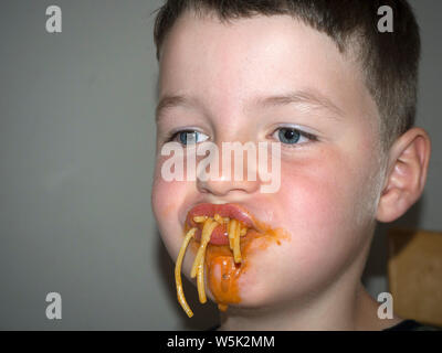 Junge herum und Grimassen, während er isst Spaghetti Bolognese Stockfoto