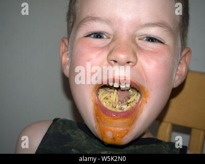 Junge herum und Grimassen, während er isst Spaghetti Bolognese Stockfoto