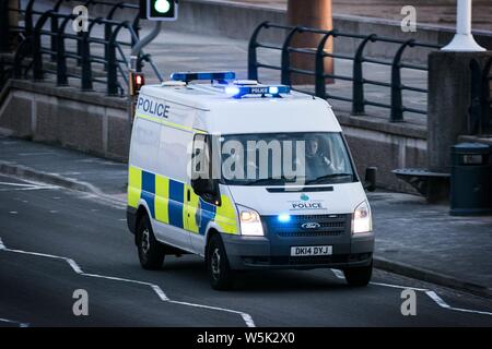 Einen Polizeiwagen hetzen, um zu einem Notfall mit Blaulicht und Sirenen entlang der Promenade in Southport, Merseyside. Stockfoto