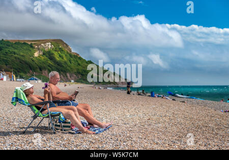 Ende Juli, ein Paar am Strand entspannen bei Seaton in South East Devon. Stockfoto