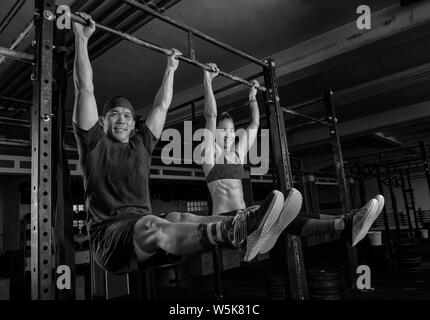 Eine athletische Paar tut ein Fitnesstraining zusammen und Spaß haben. Der muskulösen und attraktiven Mann und Frau tun die Übung l sitzen. Stockfoto