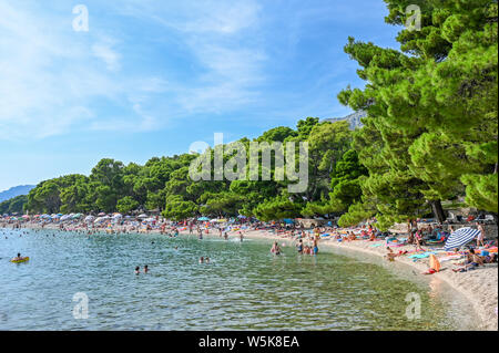 Touristen genießen den Strand von Brela. Die Riviera von Makarska in Kroatien ist bekannt für seine schönen Kiesstränden und kristallklarem Wasser. Stockfoto