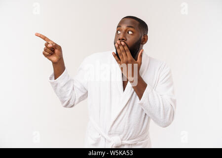 Schwarze Kerl trägt einen Bademantel Zeigefinger mit Überraschung und glückliches Gefühl. Über whtie Hintergrund isoliert. Stockfoto