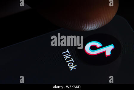 TikTok App auf dem Bildschirm des Smartphones mit sichtbaren Pixel und die Finger über Sie zu starten. Stockfoto