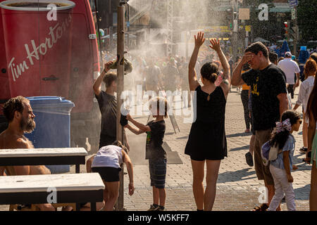 Montreal, CA - 27. Juli 2019: Menschen gehen unter Beschlag System abkühlt (Nebel Kühlsystem) während der Hitzewelle in Quartier des Festivals. Stockfoto