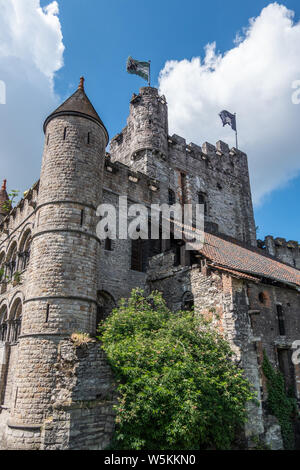 Gent, Flandern, Belgien - 21. Juni 2019: grauen Stein Turm und andere Strukturen der Gravensteen, historischen mittelalterlichen Burg der Stadt gegen den blauen Himmel mit Stockfoto