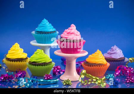 Regenbogenfarbige Frosted Chocolate Cupcakes mit Konfetti und Bögen für eine Partei Stockfoto
