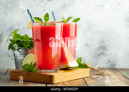 Wassermelone Slushie mit Limette und Minze, sommerlicher erfrischender Drink in hohen Gläsern auf hellblauem Hintergrund. Süßer, kalter Smoothie mit Kopierplatz Stockfoto
