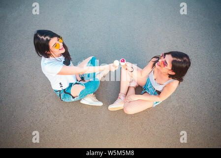 Zwei junge weibliche Freunde genießen Eis Stockfoto