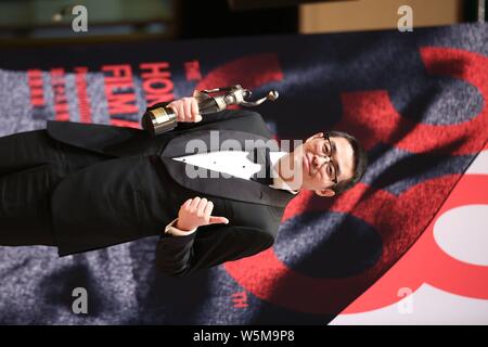 Der chinesische Regisseur Wen Muye wirft mit Trophäe für den "Besten Film aus dem Festland China und Taiwan: Sterben an der 38th Hong Kong Film Awards (HKFA zu Überleben" Stockfoto