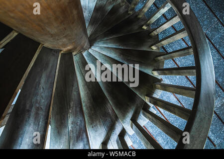 Detail der hölzerne Wendeltreppe, abstrakte geometrische Tapeten in dunklen Tönen. Runde Treppe. Hintergrund mit abstrakten Linien. Stockfoto