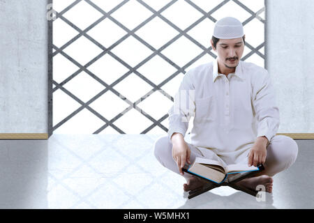 Asiatische muslimischen Mann sitzt und den Koran gelesen im Inneren der Moschee Stockfoto