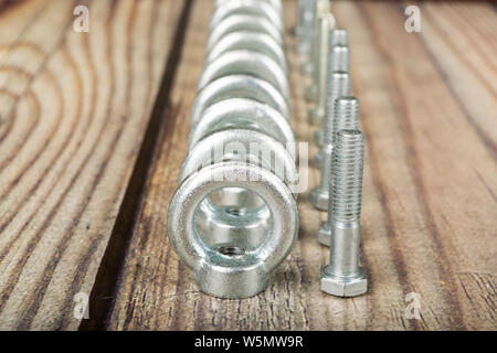 Ringmuttern mit Schrauben, verzinkt auf Holz- Hintergrund. Stockfoto
