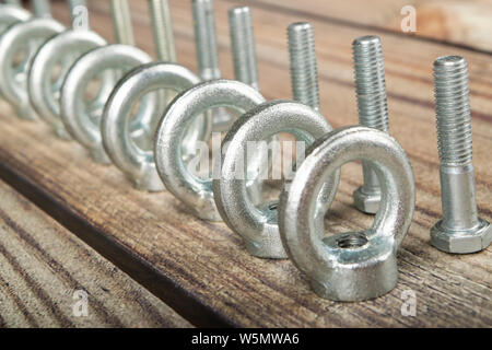 Ringmuttern mit Schrauben, verzinkt auf Holz- Hintergrund. Stockfoto