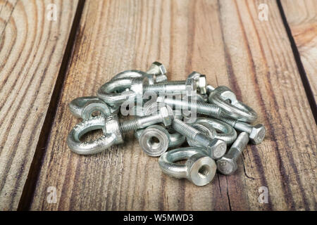 Ringmuttern mit Schrauben, verzinkt auf Holz- Hintergrund. Stockfoto