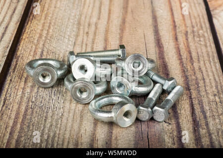 Ringmuttern mit Schrauben, verzinkt auf Holz- Hintergrund. Stockfoto