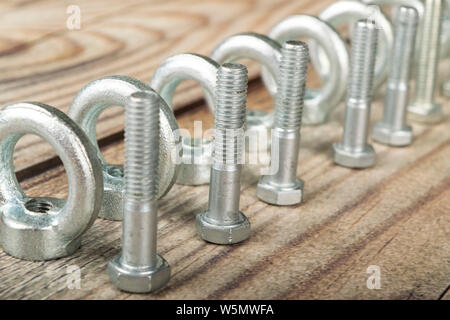 Ringmuttern mit Schrauben, verzinkt auf Holz- Hintergrund. Stockfoto