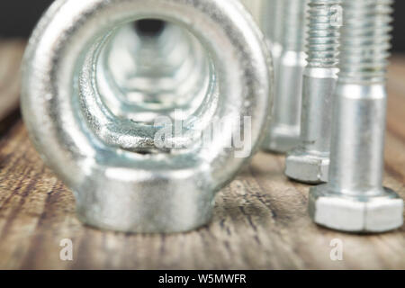 Ringmuttern mit Schrauben, verzinkt auf Holz- Hintergrund. Stockfoto