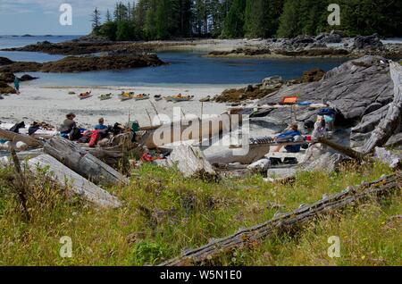 Bunsby Inseln, an der Westküste von Vancouver Island, BC, 19. Juli 2018: Kajakfahrer in Sonne auf abgelegenen Strand Campingplatz entspannen Sie nach Morgen paddeln Stockfoto