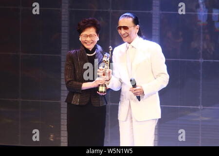 Hong Kong Chief Executive Carrie Lam Cheng Yuet-ngor präsentiert den "Lifetime Achievement Award" Trophäe zu Hong Kong Schauspieler und Produzenten Patrick Tse-duri Stockfoto