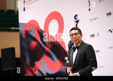 Der chinesische Regisseur Wen Muye wirft mit Trophäe für den "Besten Film aus dem Festland China und Taiwan: Sterben an der 38th Hong Kong Film Awards (HKFA zu Überleben" Stockfoto