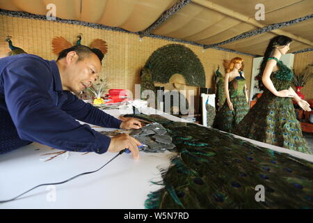 Chinesische hofbesitzers Xia Linrong zeigt ein Brautkleid aus Pfauenfedern in De' eine Grafschaft, Conghua City, der ostchinesischen Provinz Jiangxi, 16 Stockfoto