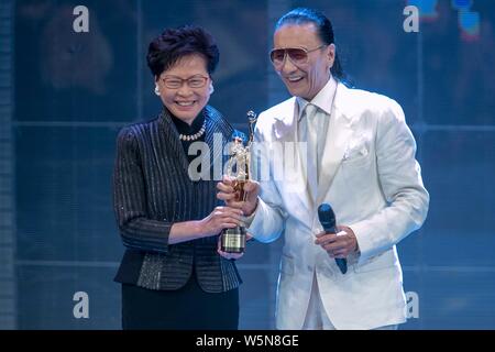 Hong Kong Chief Executive Carrie Lam Cheng Yuet-ngor präsentiert den "Lifetime Achievement Award" Trophäe zu Hong Kong Schauspieler und Produzenten Patrick Tse-duri Stockfoto