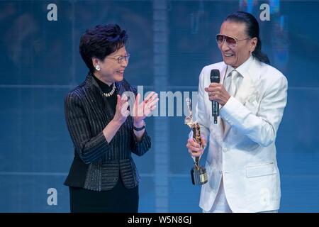 Hong Kong Chief Executive Carrie Lam Cheng Yuet-ngor präsentiert den "Lifetime Achievement Award" Trophäe zu Hong Kong Schauspieler und Produzenten Patrick Tse-duri Stockfoto