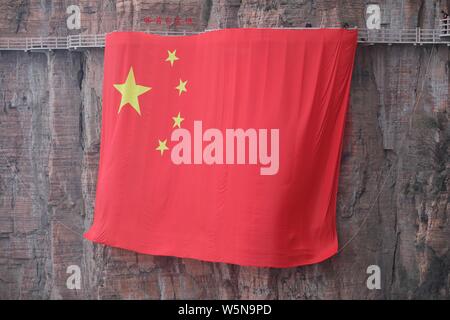 Chinesische Arbeiter hängen einen großen nationalen Flagge der 70. Jahrestag der Gründung der Volksrepublik China entlang einer Klippe zu markieren am Taihang Stockfoto