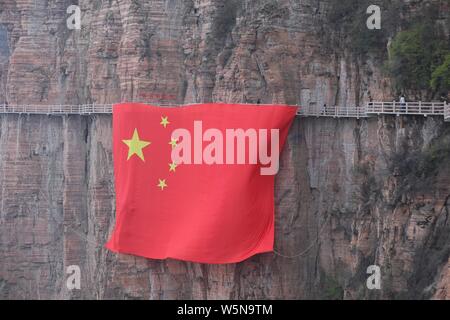 Chinesische Arbeiter hängen einen großen nationalen Flagge der 70. Jahrestag der Gründung der Volksrepublik China entlang einer Klippe zu markieren am Taihang Stockfoto