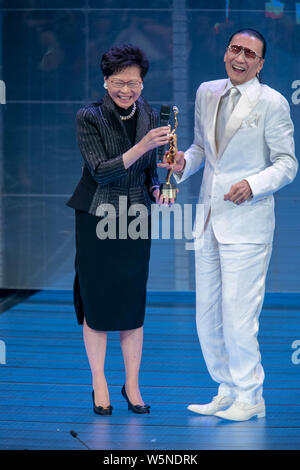 Hong Kong Chief Executive Carrie Lam Cheng Yuet-ngor präsentiert den "Lifetime Achievement Award" Trophäe zu Hong Kong Schauspieler und Produzenten Patrick Tse-duri Stockfoto