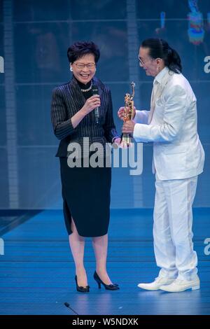 Hong Kong Chief Executive Carrie Lam Cheng Yuet-ngor präsentiert den "Lifetime Achievement Award" Trophäe zu Hong Kong Schauspieler und Produzenten Patrick Tse-duri Stockfoto