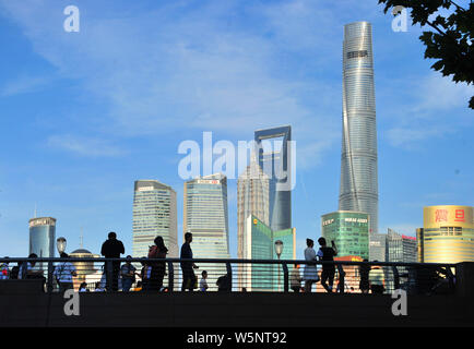 Touristen besuchen die Promenade am Bund entlang des Flusses Huangpu den Oriental Pearl TV Tower zu sehen, links am höchsten, dem Shanghai Tower, rechts am höchsten, Stockfoto