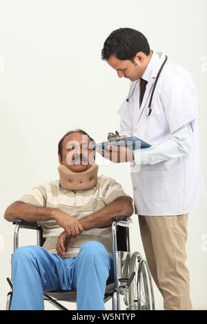 Arzt mit Patient, der Nackenstütze im Rollstuhl trägt Stockfoto