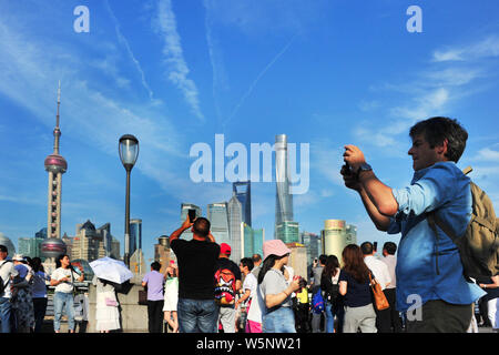 Touristen besuchen die Promenade am Bund entlang des Flusses Huangpu den Oriental Pearl TV Tower zu sehen, links am höchsten, dem Shanghai Tower, rechts am höchsten, Stockfoto