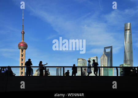 Touristen besuchen die Promenade am Bund entlang des Flusses Huangpu den Oriental Pearl TV Tower zu sehen, links am höchsten, dem Shanghai Tower, rechts am höchsten, Stockfoto