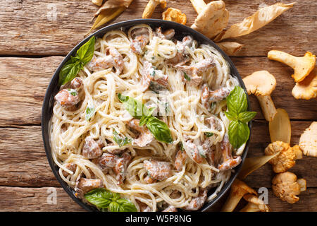 Spaghetti mit Pfifferlingen in Sahnesauce mit Basilikum close-up auf einem Teller auf den Tisch. Horizontal oben Ansicht von oben Stockfoto