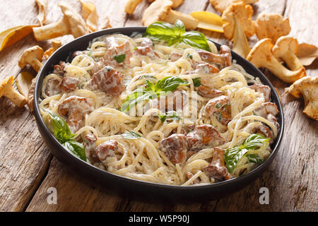 Spaghetti Nudeln mit gebratenen Pfifferlingen in einer cremigen Sauce mit Käse close-up auf einem Teller auf den Tisch. Horizontale Stockfoto